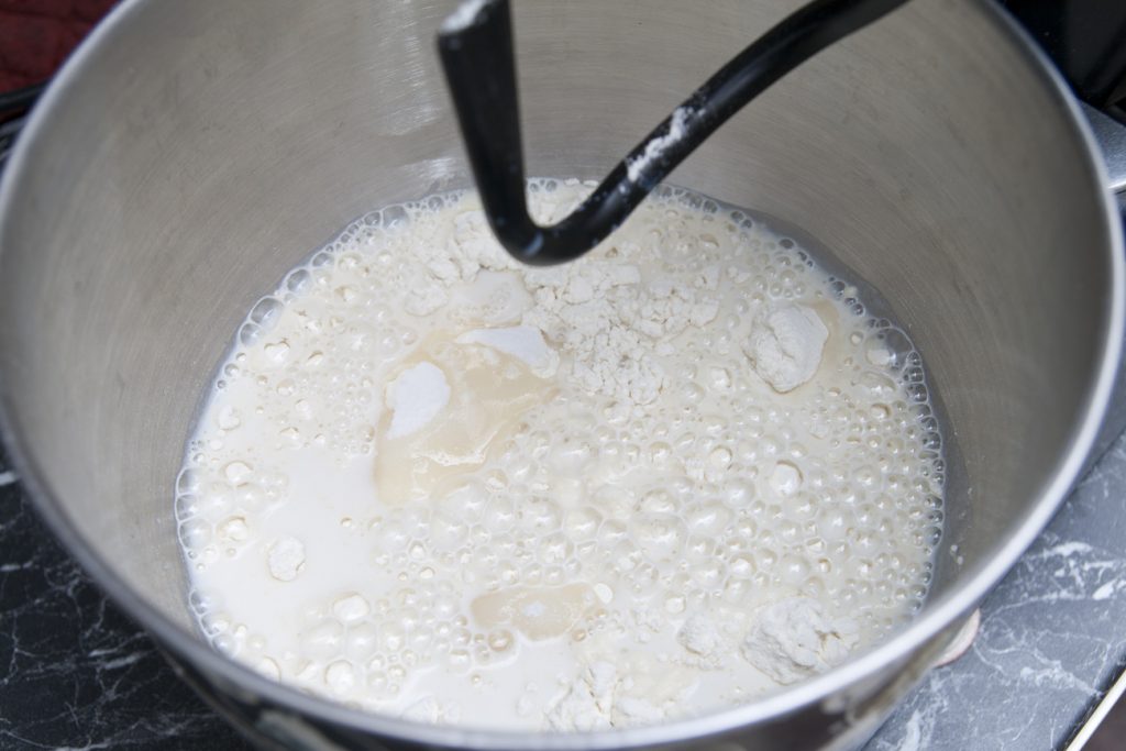 Versare latte nella scodella della planetaria assieme alla farina